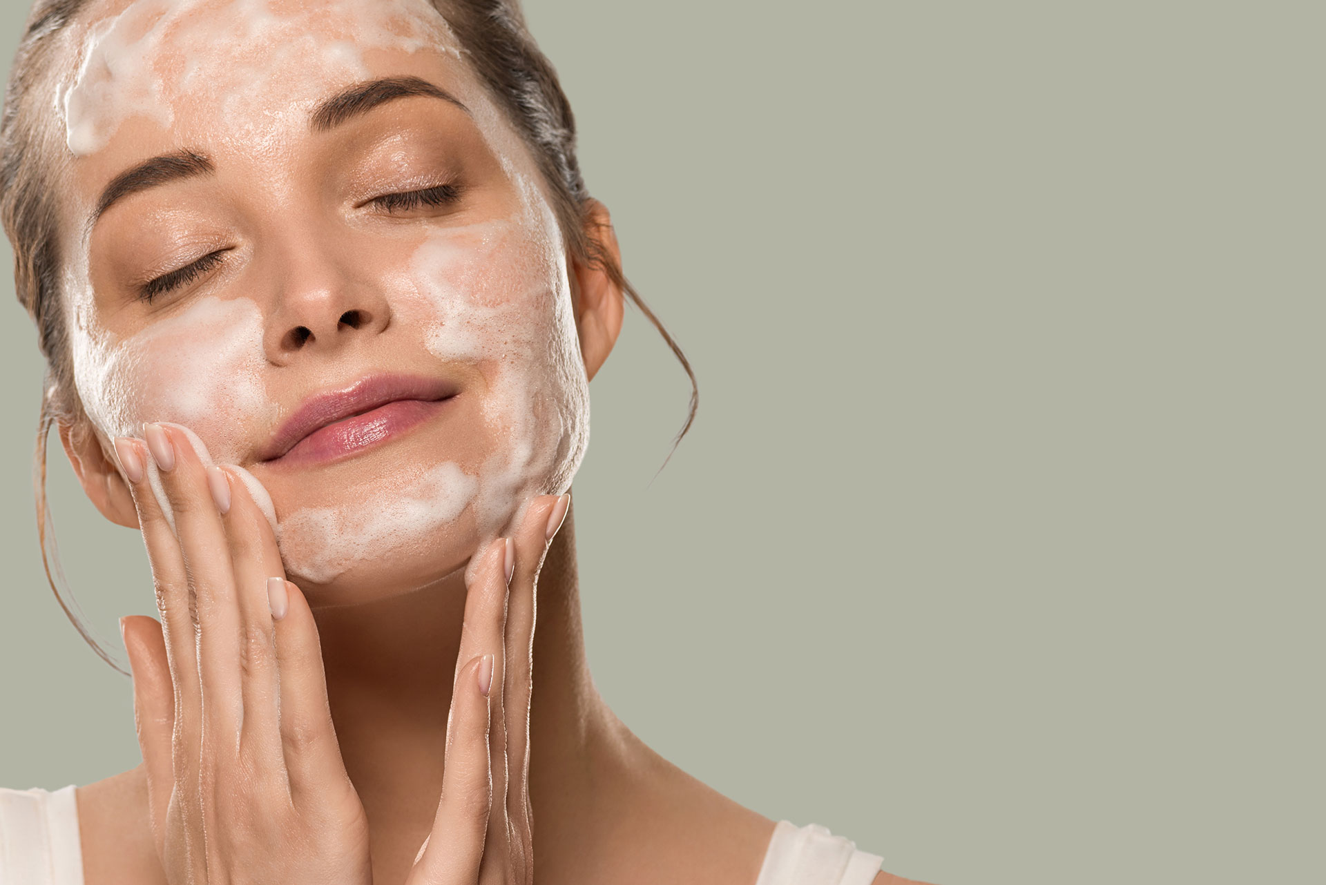 Woman gently cleansing her face with professional skincare at IRIS Aesthetics in Longmont, CO